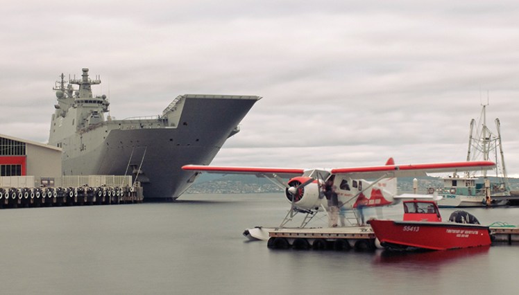 HMAS Canberra looms over the Tasmanian Air Adventures plane in Sullivan's Cove.