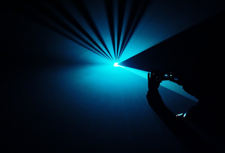 Fingers break through the shaft of light.