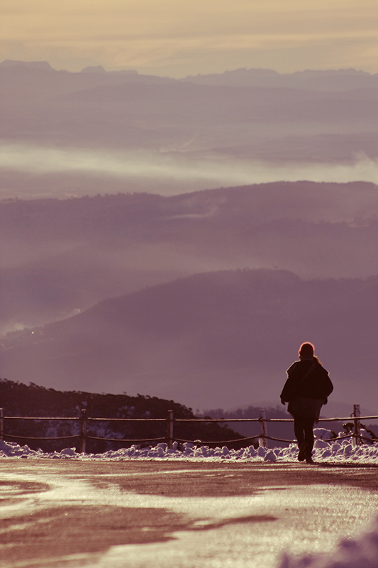 A lady ventures back down the mountain, layer after layer of hills before her. 
